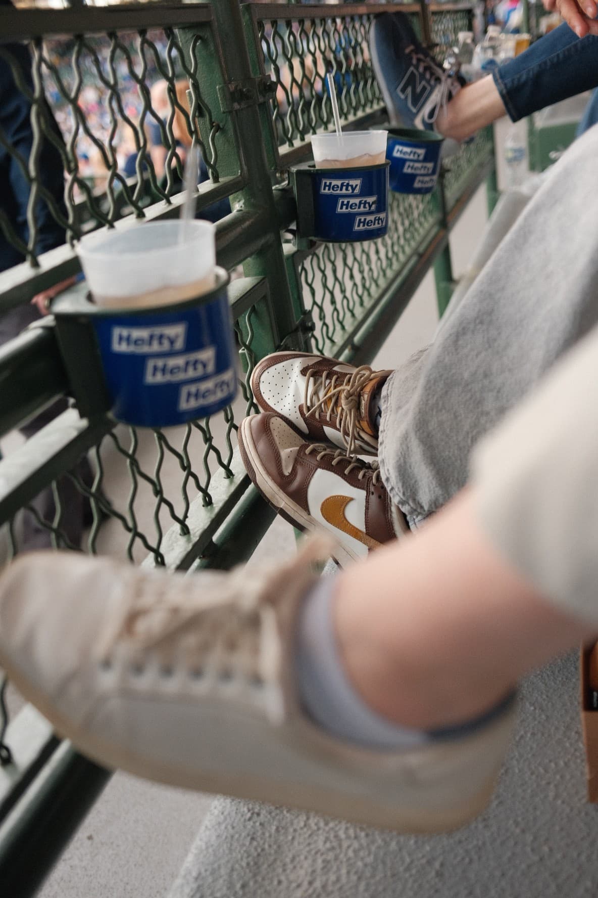 Sneakers propped on the rail beside Hefty cup holders at Wrigley Field