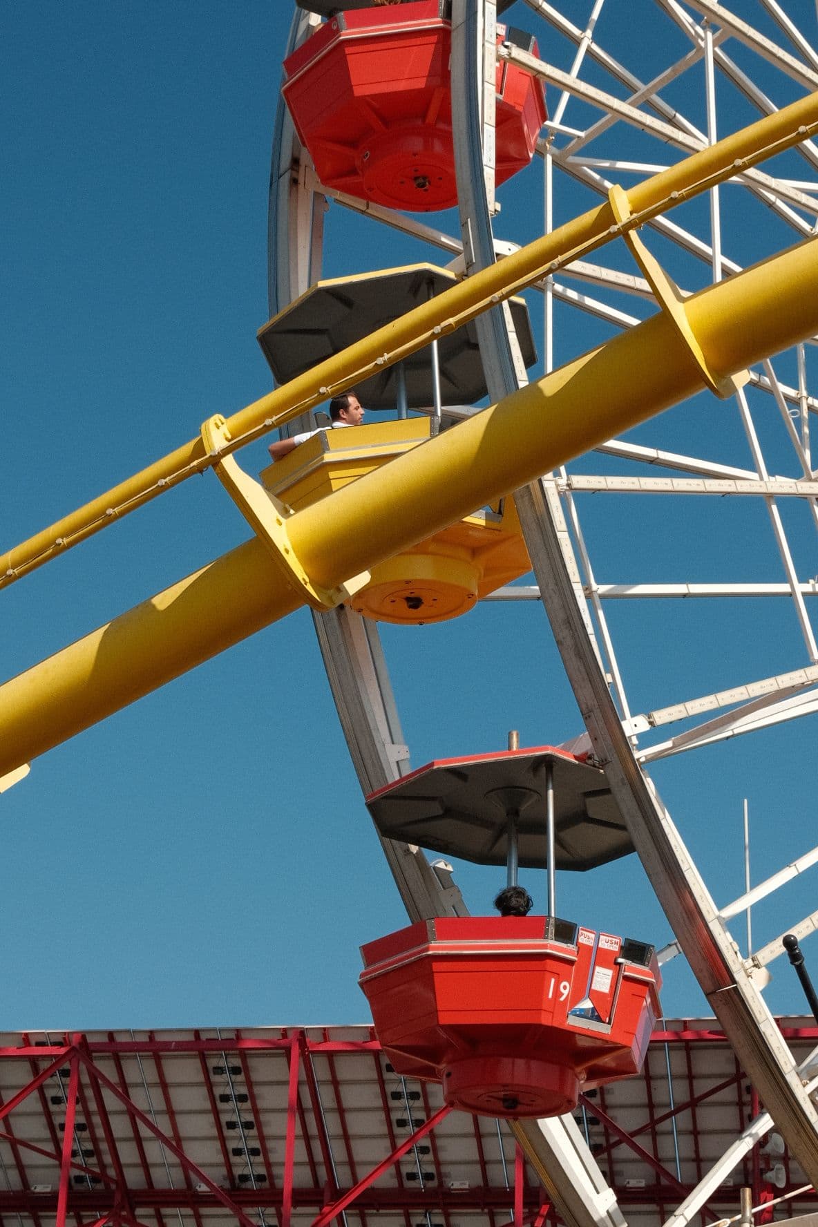Close-up of red and yellow Ferris wheel cars against a blue sky